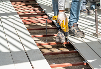 Worker using a drill to install composite decking by a pool in West Hollywood.